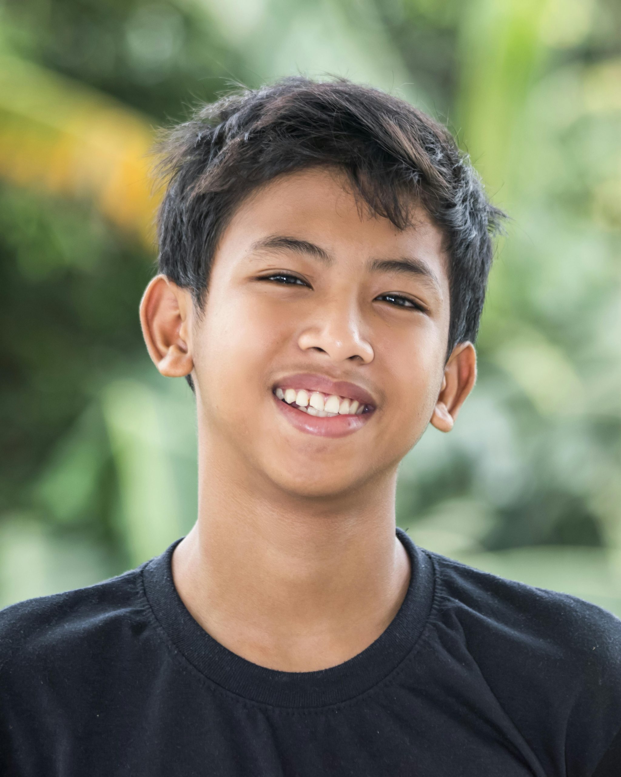 Happy Asian boy smiling in outdoor setting, capturing joy and innocence.